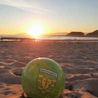 A view of a football sitting on a sandy beach at sunset