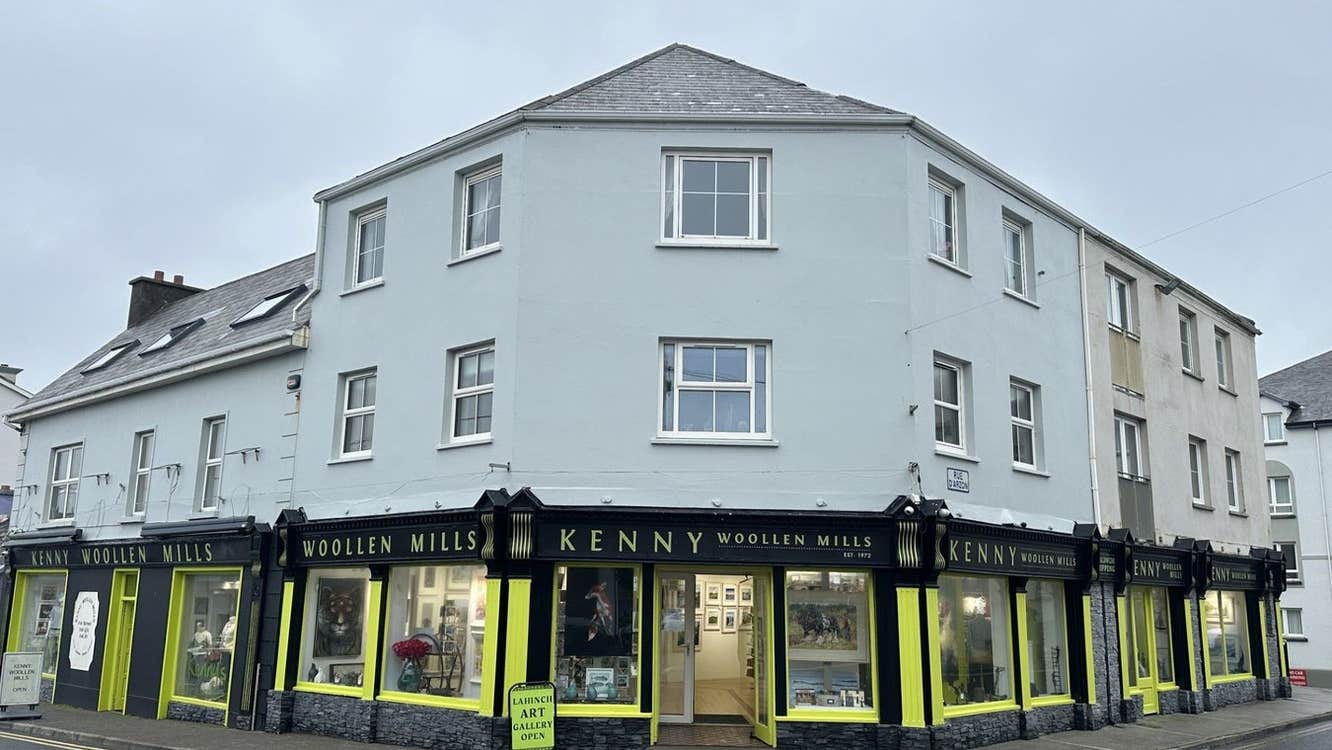 A two storey building on a street with a business name along the top of the door and windows