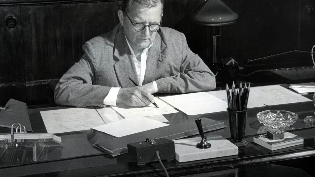 Composer Dmitri Shostakovich - black and white old photo of a man seated at a desk, writing