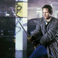 A man wielding a katana in a parking lot.