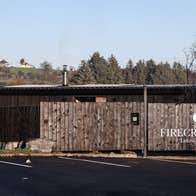 Wooden fencing around an outdoor sauna with trees in the background