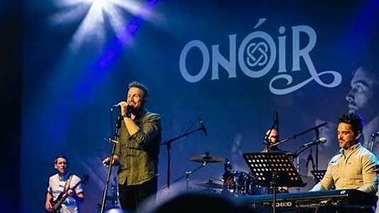 4 men playing and singing on stage.