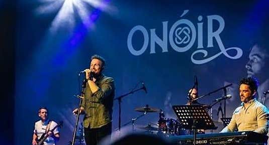 4 men playing and singing on stage.