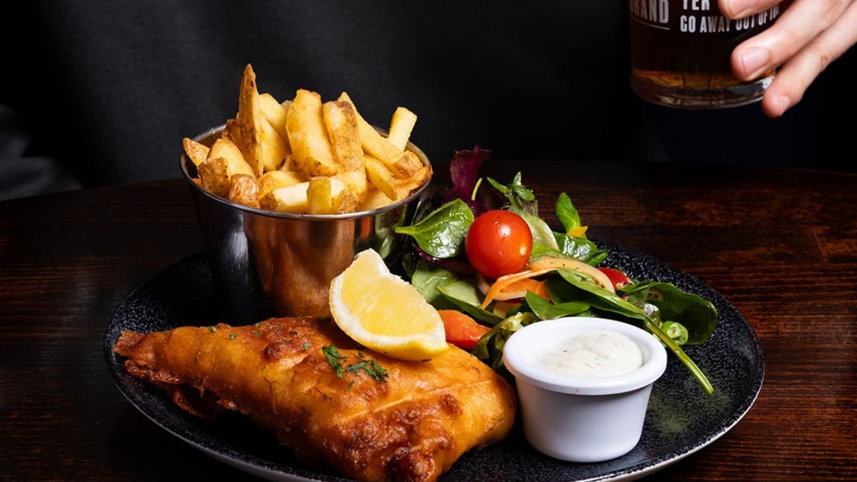 A plate with fish and chips garnished with a salad