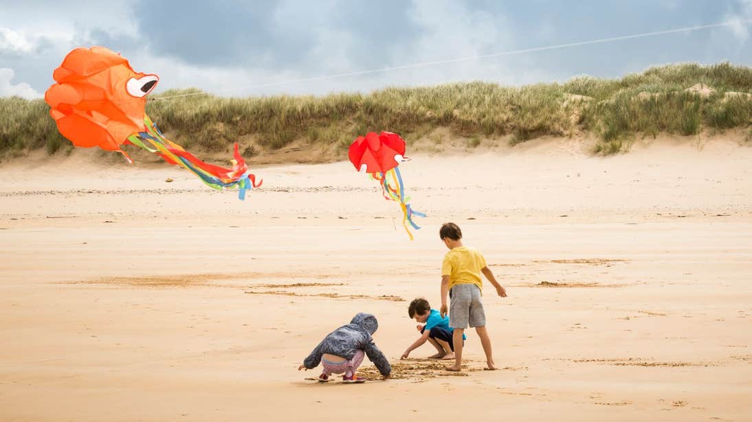 Three children flying colourful kites on Marble Hill Beach