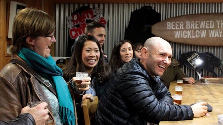 Group sitting at a wooden beer tasting table with glasses in front of them