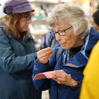 Person holding a small plastic spoon sampling food from a red and white napkin