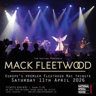 Distant view of a stage, with person dressed in white with arms outstretched and other band members, lit from above by many downward spotlights