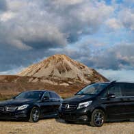 Two black Mercedes vehicles parked in front of a mountain