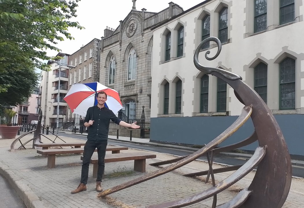 Person holding an umbrella standing on a street with wooden seats