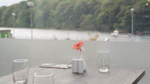 Table overlooking the water with glasses and flower vase on the table