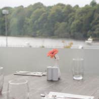 Table overlooking the water with glasses and flower vase on the table