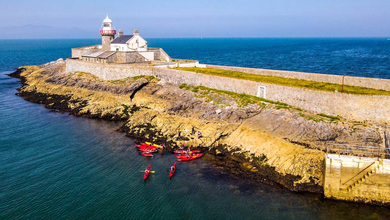 Aerial view of a group of kayakers near a lighthouse