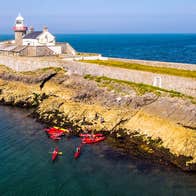 Aerial view of a group of kayakers near a lighthouse