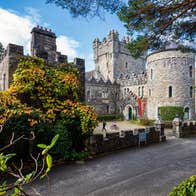 A castle and round tower surrounded by green shrubbery