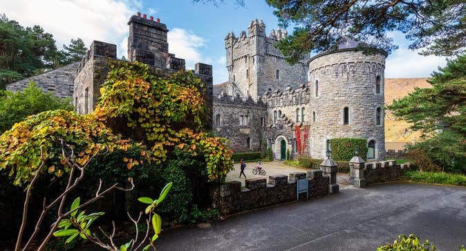 A castle and round tower surrounded by green shrubbery