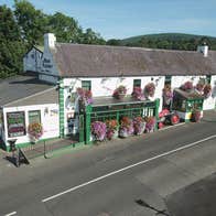 The exterior of the Merry Ploughboy Pub which is a white building with green trim and shopfront.