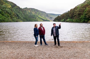 A tour guide and a couple standing at a lake shore