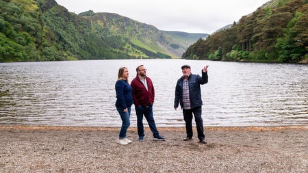 A tour guide and a couple standing at a lake shore