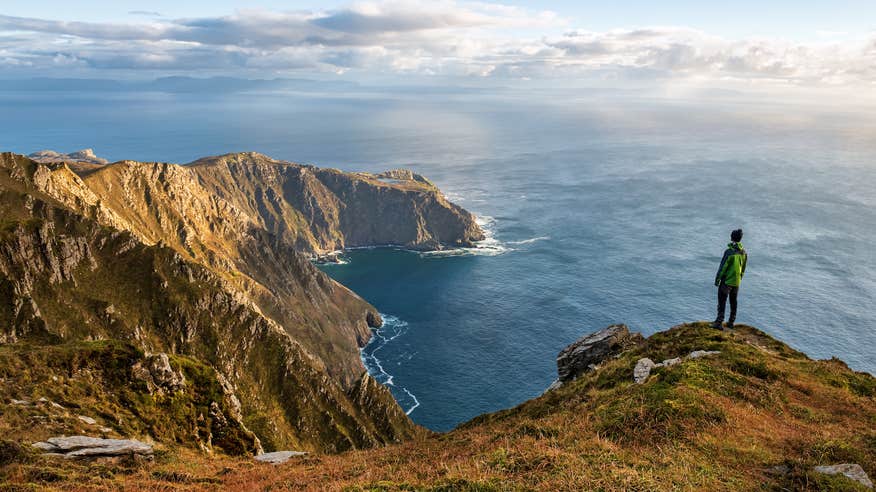 A person looking out at the sea from the edge of Sliabh Liag (Slieve League) in County Donegal.