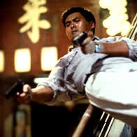 A man sliding down a banister, with a pistol in each hand.