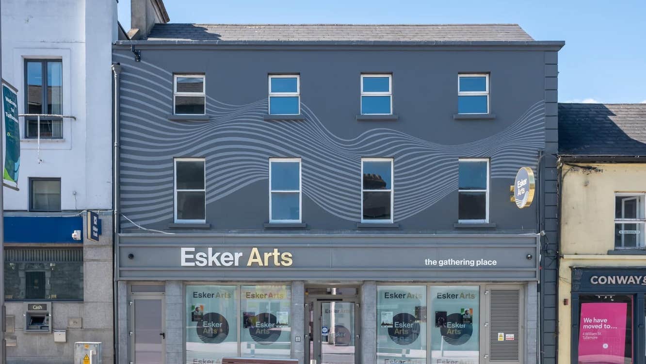 Grey exterior of a building on a street with two benches in front