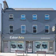 Grey exterior of a building on a street with two benches in front