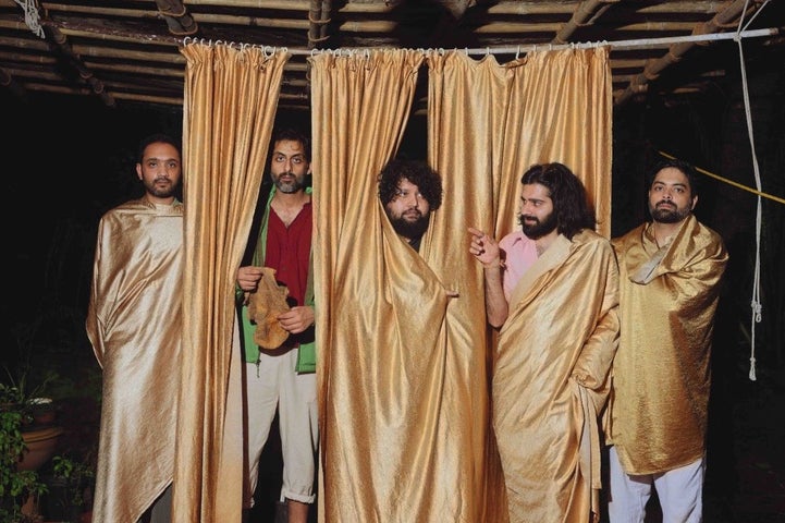 5 men with dark beards, some partially obscured by gold curtains hanging down from a wire above their heads.