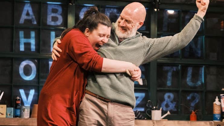 A joyful woman is hugging a smiling man who is holding a fist up in the air