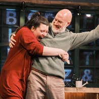 A joyful woman is hugging a smiling man who is holding a fist up in the air
