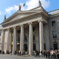 A tour group outside a stately building on a busy city street