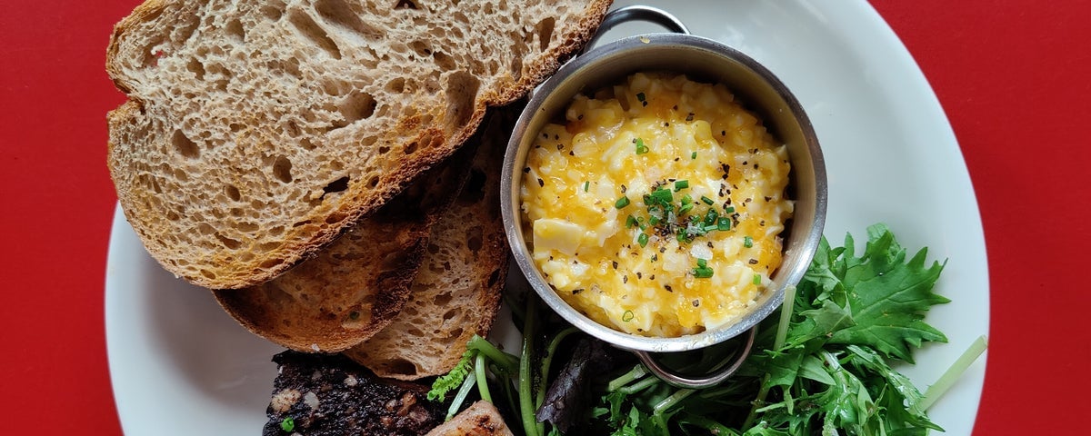 An egg dish with brown bread and green leaves on a plate