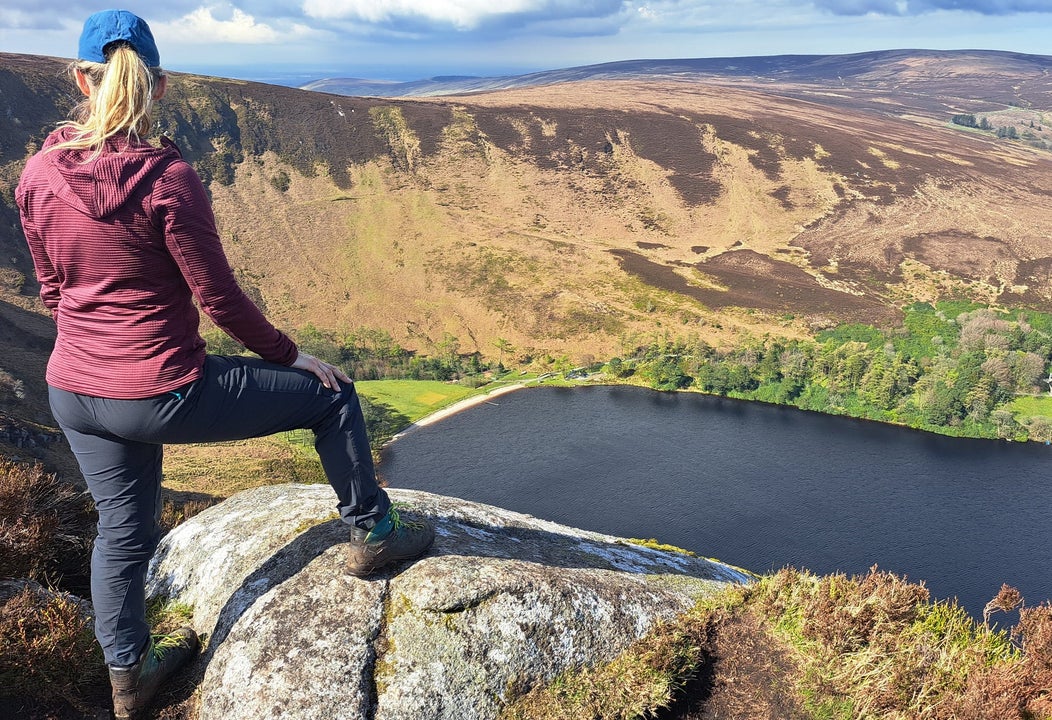 Person leaning on a rock looking down at a mountain valley