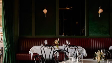 Tables set for dinner in a restaurant with dark green background