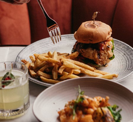 Food on plates with a drink in between and a fork about to pick up food