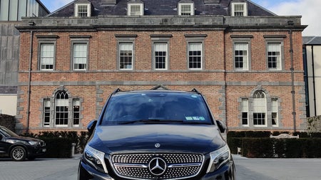 A luxury car parked in front of a large period building