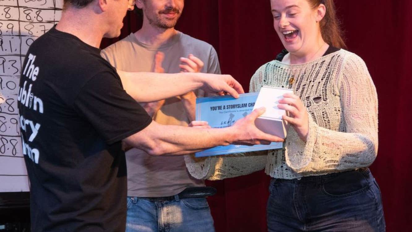 A man presenting a small box and certificate to a surprised looking woman.
