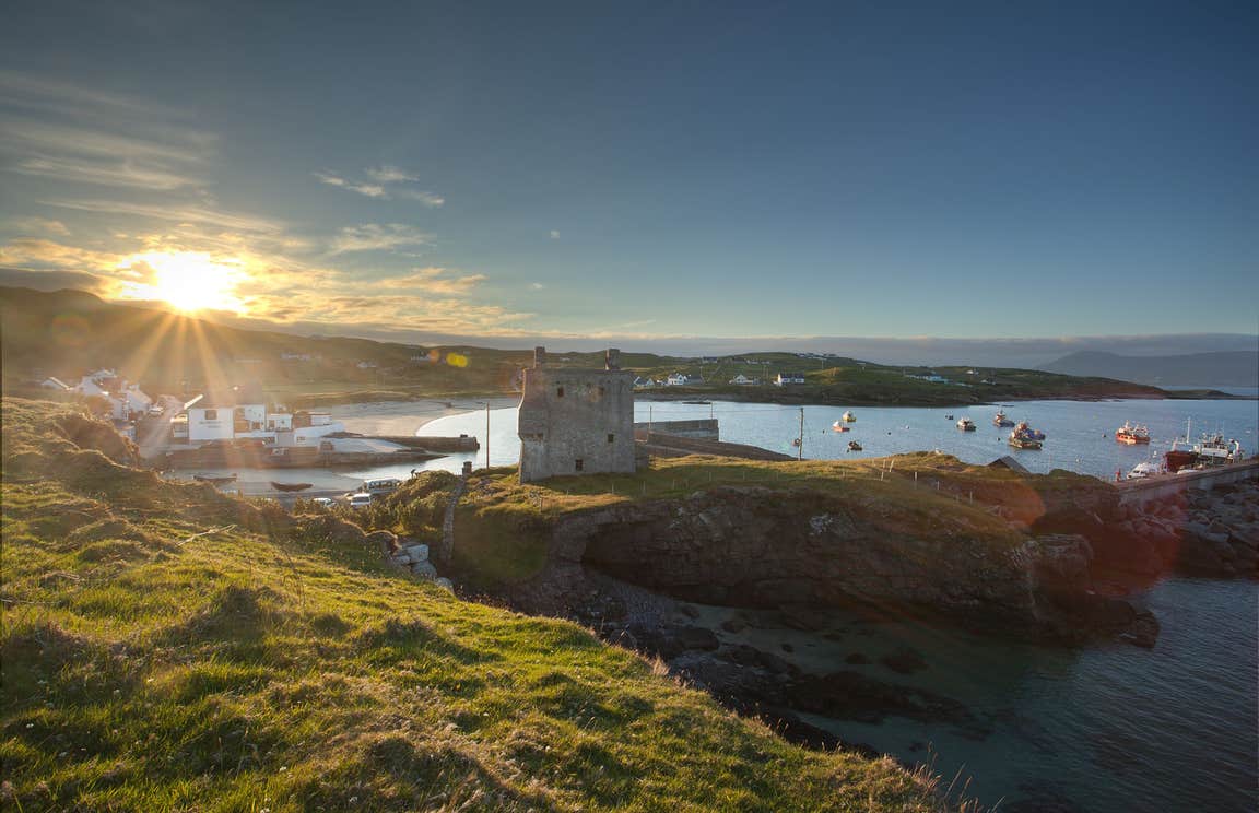 A view of the sun over Clare Island, Mayo with boats bobbing on the water in the background