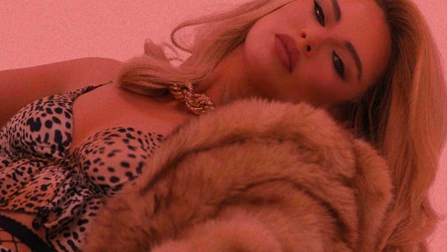 Pink tinted photo of person reclining back with a fur coat,