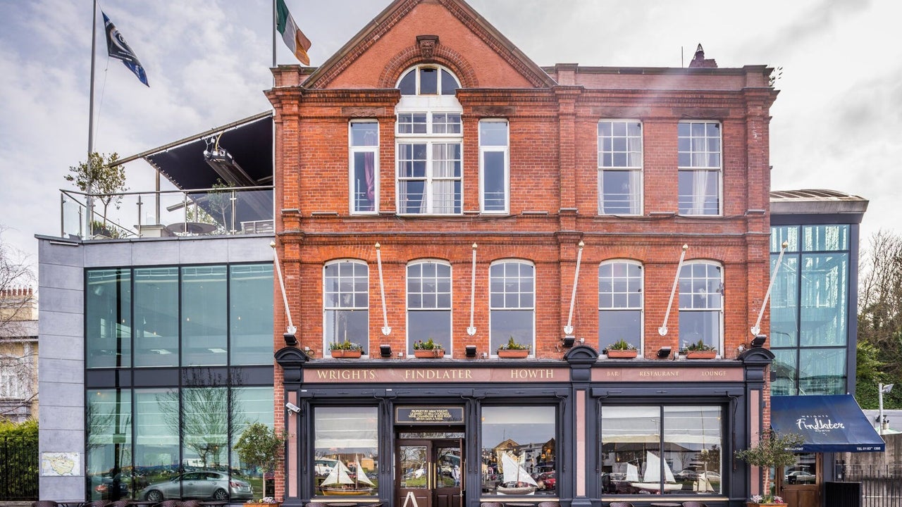 The exterior of a red brick building with glass extension and roof terrace