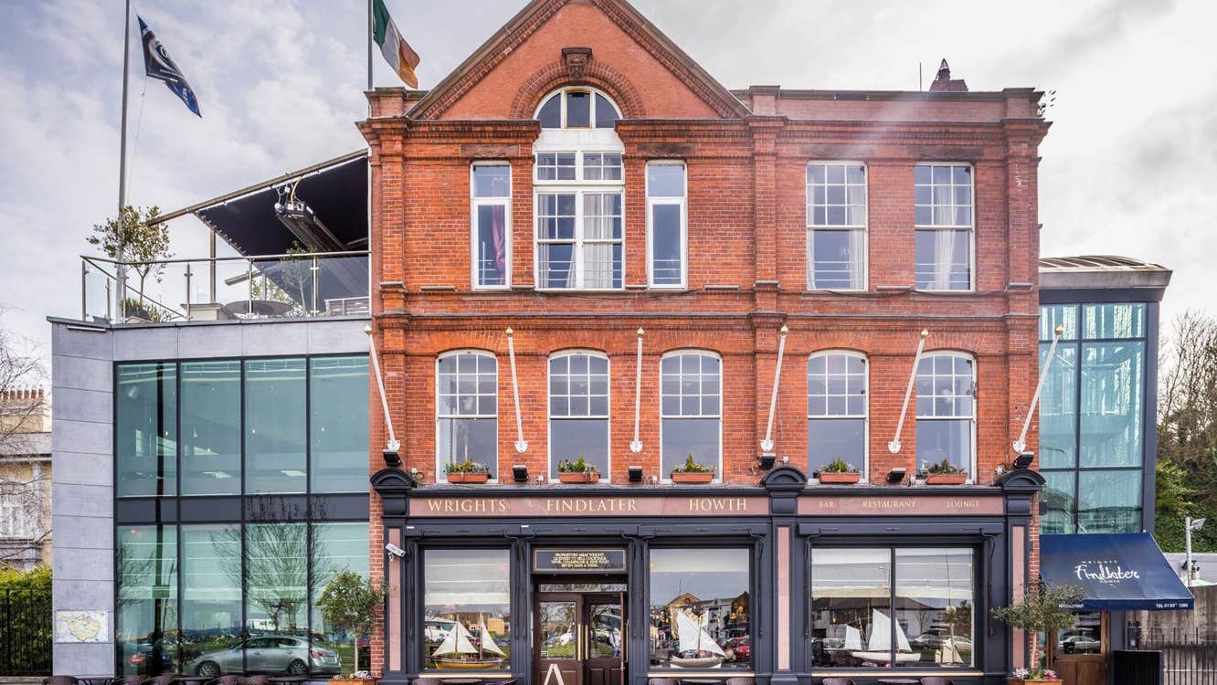The exterior of a red brick building with glass extension and roof terrace