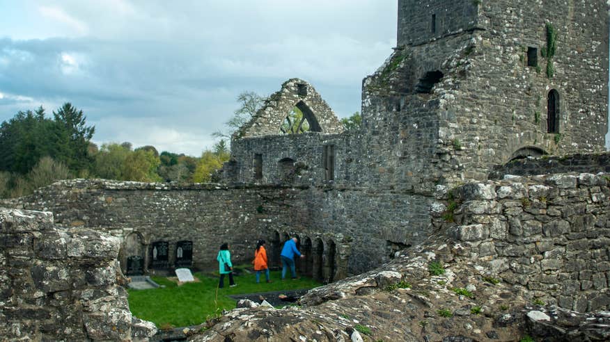 Three people exploring Creevelea Friary in Dromahair, County Leitrim