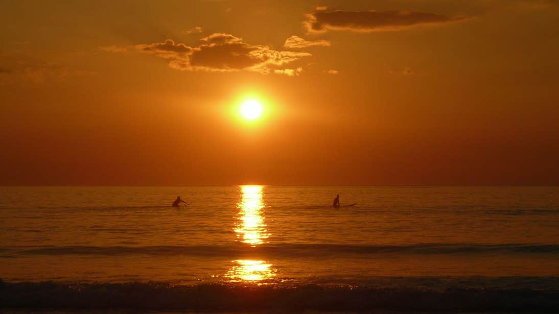 Two surfers paddling in the ocean at sunset in Strandhill, Sligo