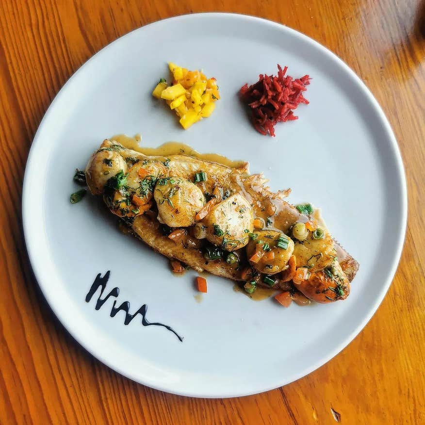 A plate of fish served with vegetables and garnishes.