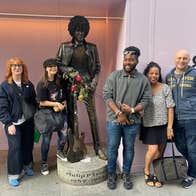 A walking group pose alongside a statue of the musician Phil Lynott