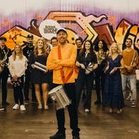 A large group of smiling people, most holding musical instruments.