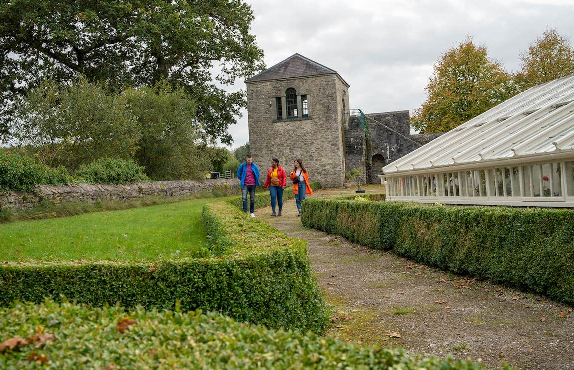 Three people walking through the grounds of Strokestown House and Park in County Roscommon.