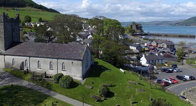 An old church on a small hill overlooking a town with the sea in the distance