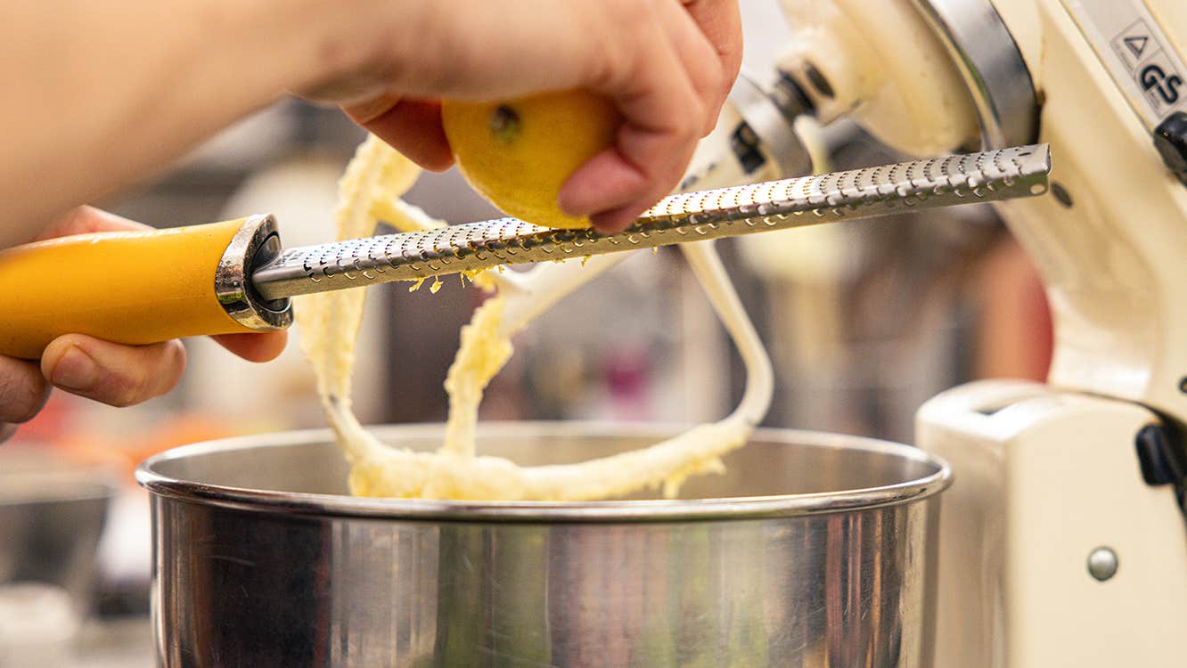 Christmas Cakes & Sweet Treats. A pair of hands grating a lemon into a large mixer bowl.