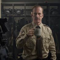 A man wearing a sheriff's uniform is in an armoury. He is holding a mug.